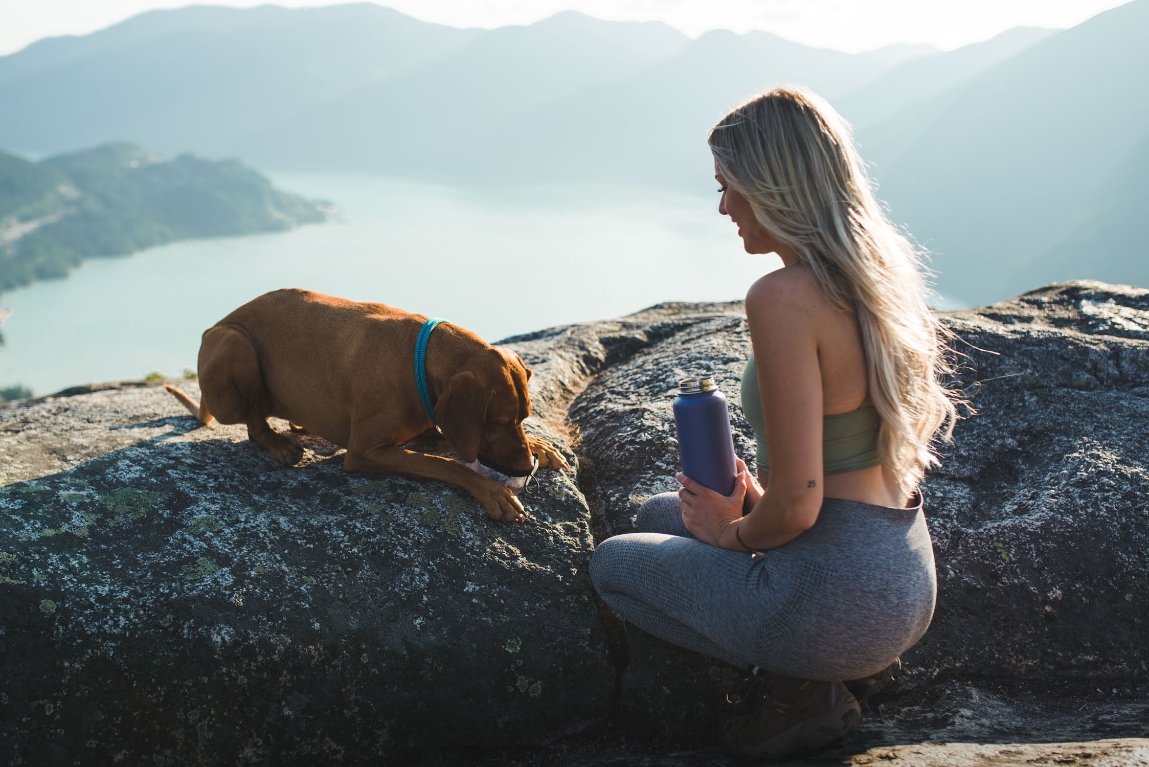 girl pouring water for her brown dog drinking out of the white atlas pet company lifetime bowl on rocky overlook