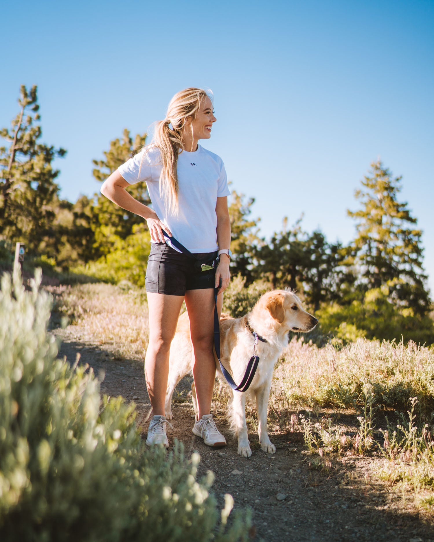 Girl standing on hiking trail with golden retriever wearing the lifetime lite adjustable hands-free lifetime lite leash