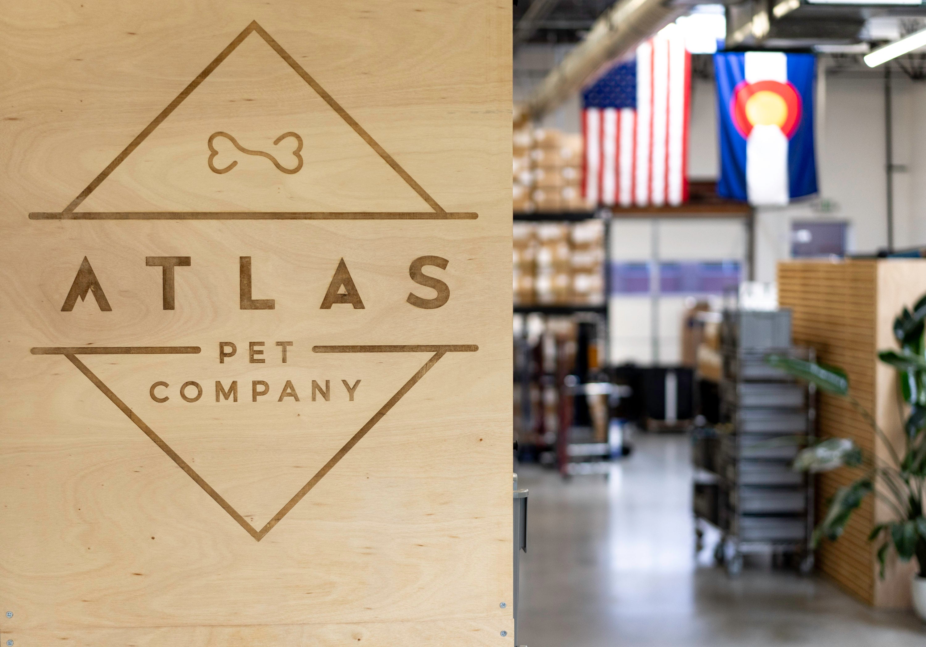 atlas pet company warehouse logo sign with colorado flags and american flag in background