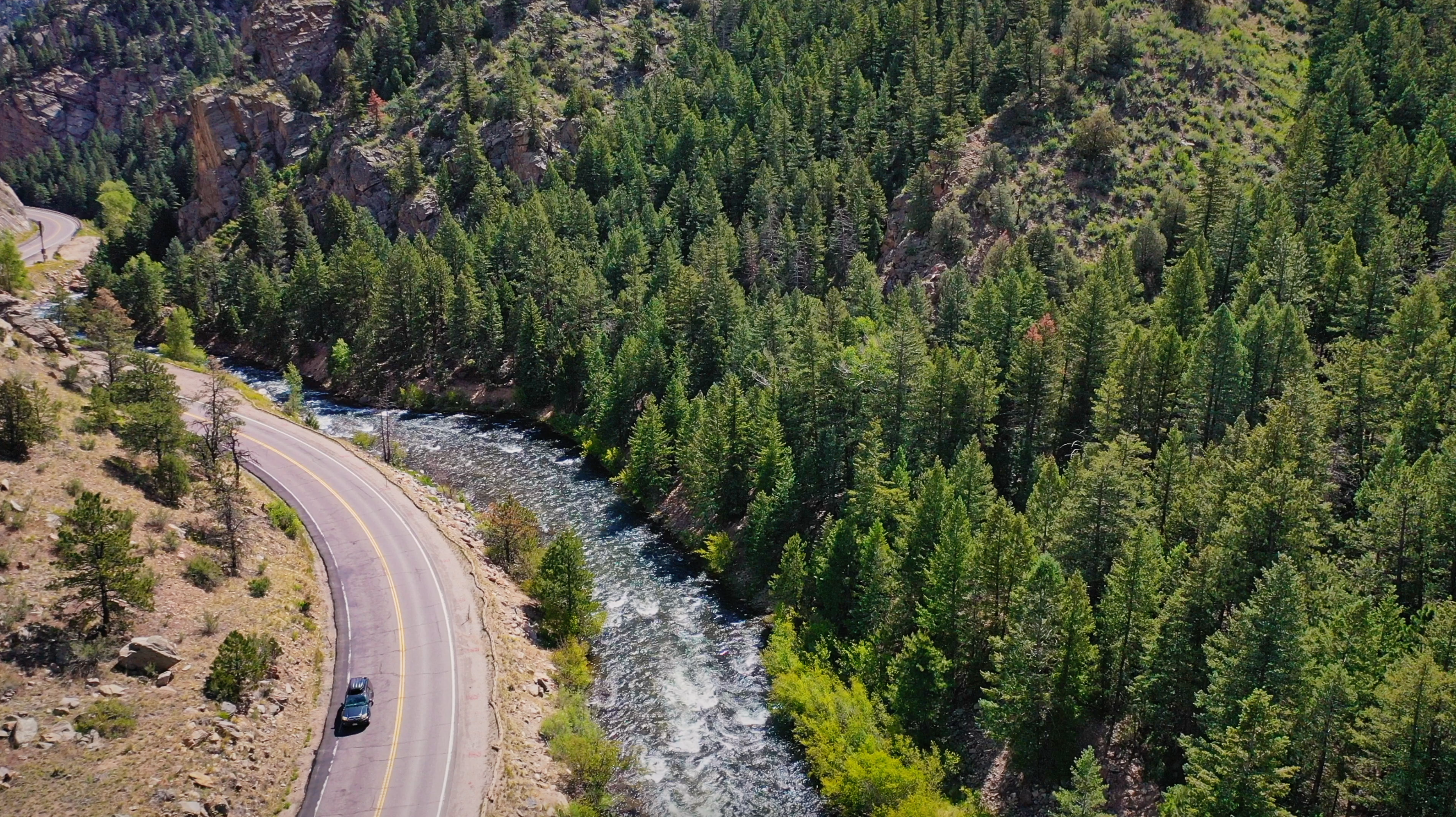 car driving on mountain road along a river